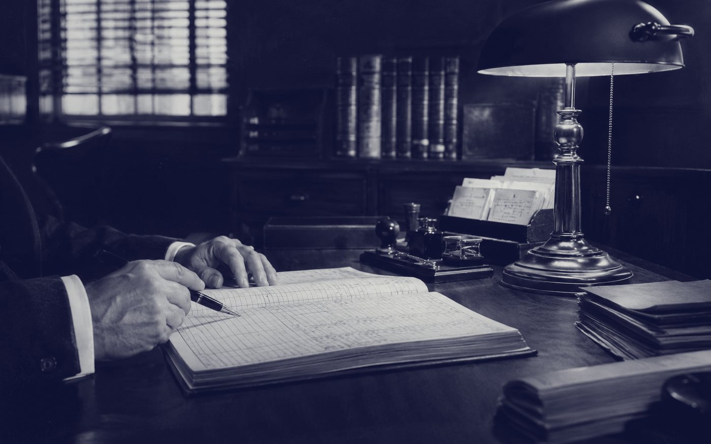 A banker reviews a loan ledger by lamplight